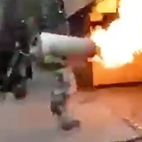 Bombero carga tanque de gas en llamas para evitar explosión